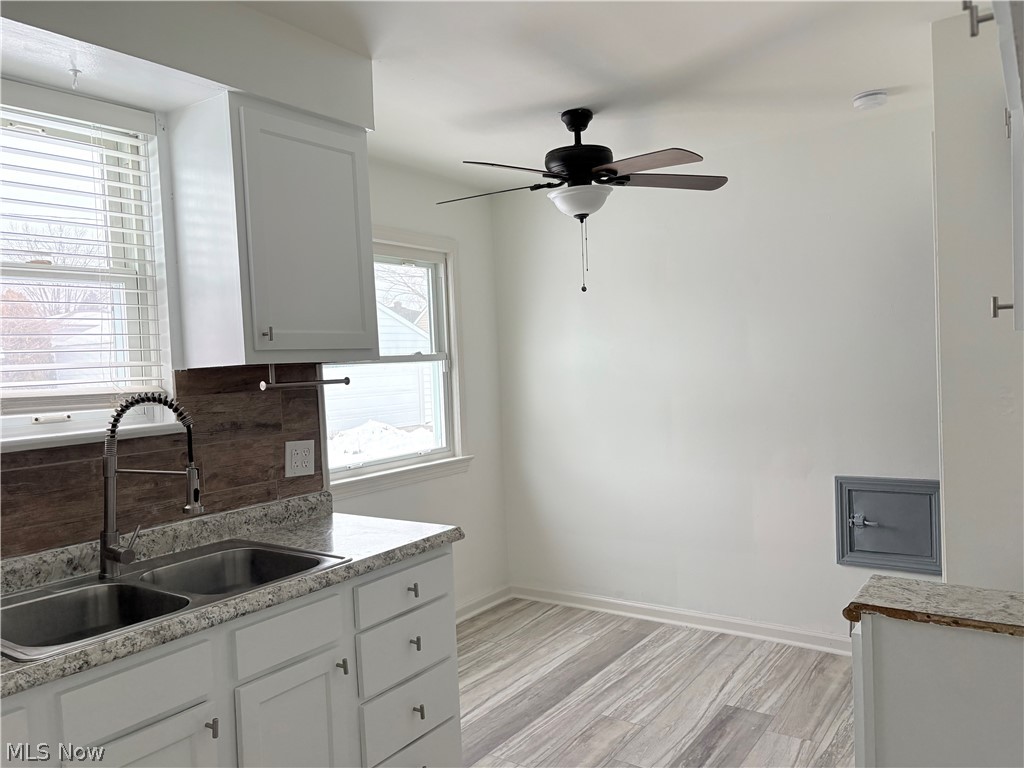 15521 Corkhill Road Maple Heights, OH 44137 - Photo 5 of 33 Kitchen with white cabinetry, light wood-type flooring, a ceiling fan, and light stone countertops