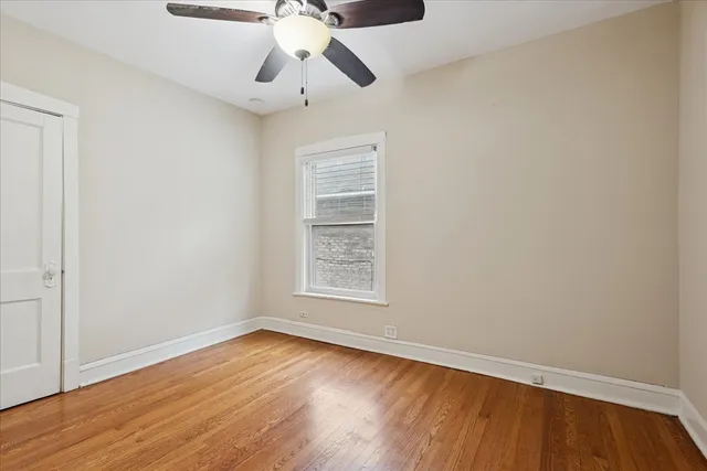 an empty room with wooden floor chandelier fan and windows