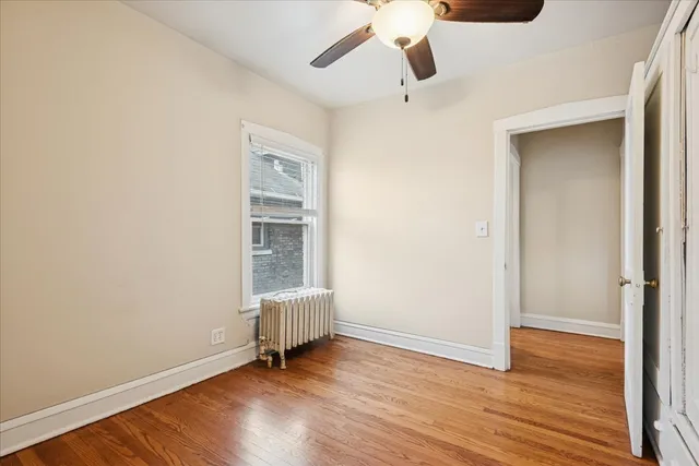 an empty room with wooden floor cabinet and windows