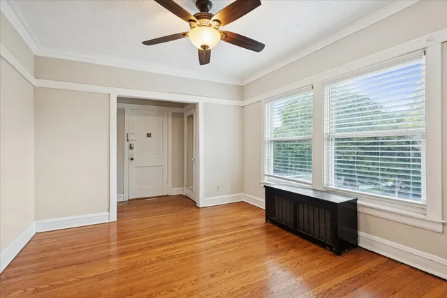 a view of an empty room with a window and wooden floor