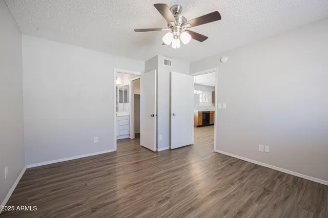 an empty room with wooden floor and ceiling fan