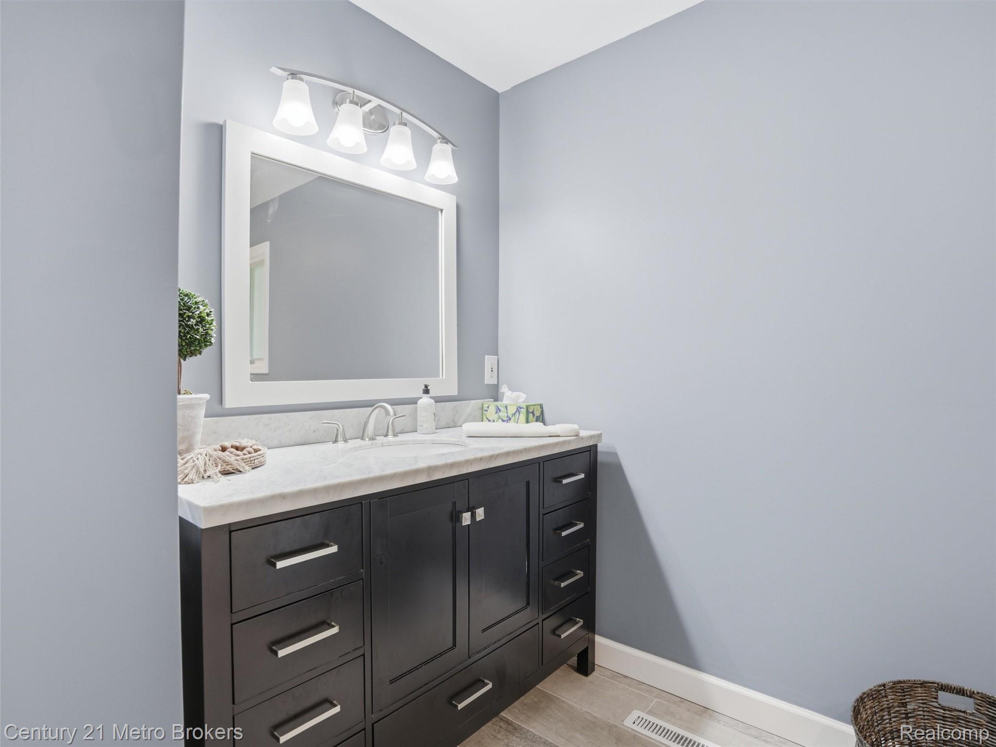 11447 North Latson Road Linden, MI 48451 - Photo 19 of 52 Bathroom vanity featuring a dark wood finish, a light-toned countertop, and a rectangular undermount sink