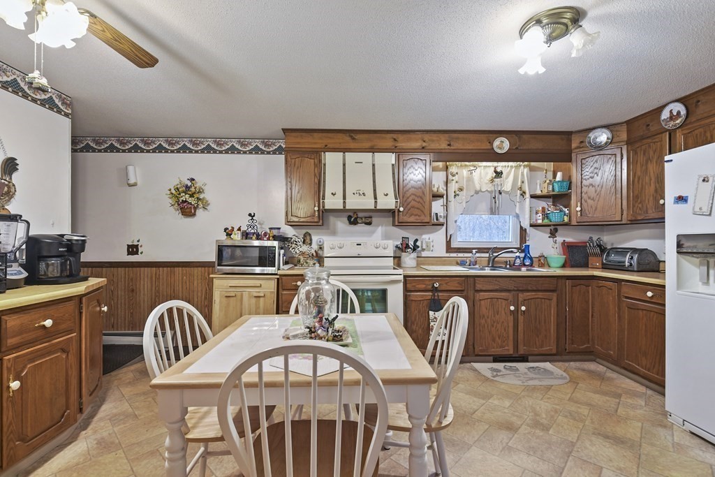 279 Little Alum Road Brimfield, MA 01010 - Photo 11 of 37 a kitchen with stainless steel appliances granite countertop a stove top oven a sink a dining table and chairs with wooden floors
