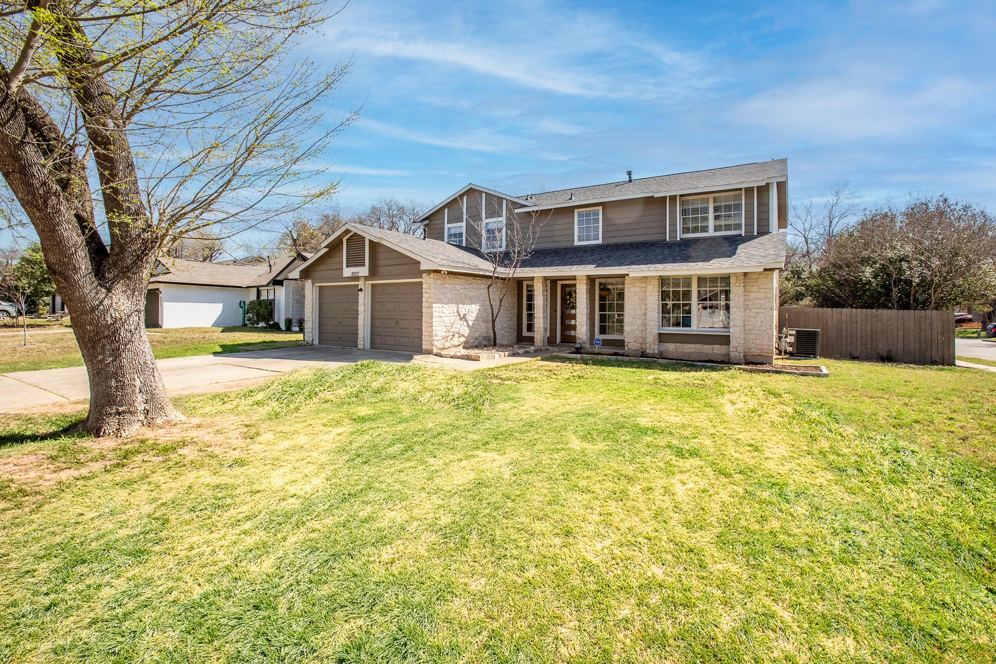 8007 Swindon Lane Austin, TX 78745 - Photo 1 of 27 The property features a two-car garage with individual doors, a stone and siding exterior, and a well-maintained lawn