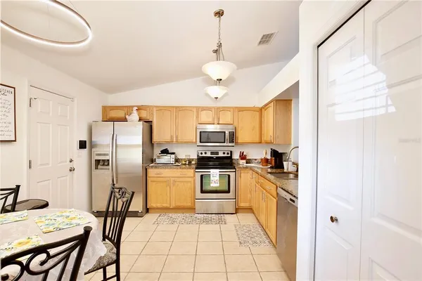 a kitchen with stainless steel appliances granite countertop a stove a refrigerator a sink dishwasher a dining table and chairs with wooden floor