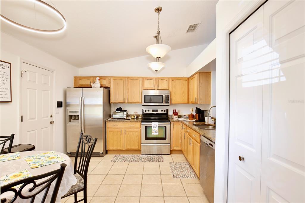 3415 Celena Circle St. Cloud, FL 34769 - Photo 6 of 20 a kitchen with stainless steel appliances granite countertop a stove a refrigerator a sink dishwasher a dining table and chairs with wooden floor