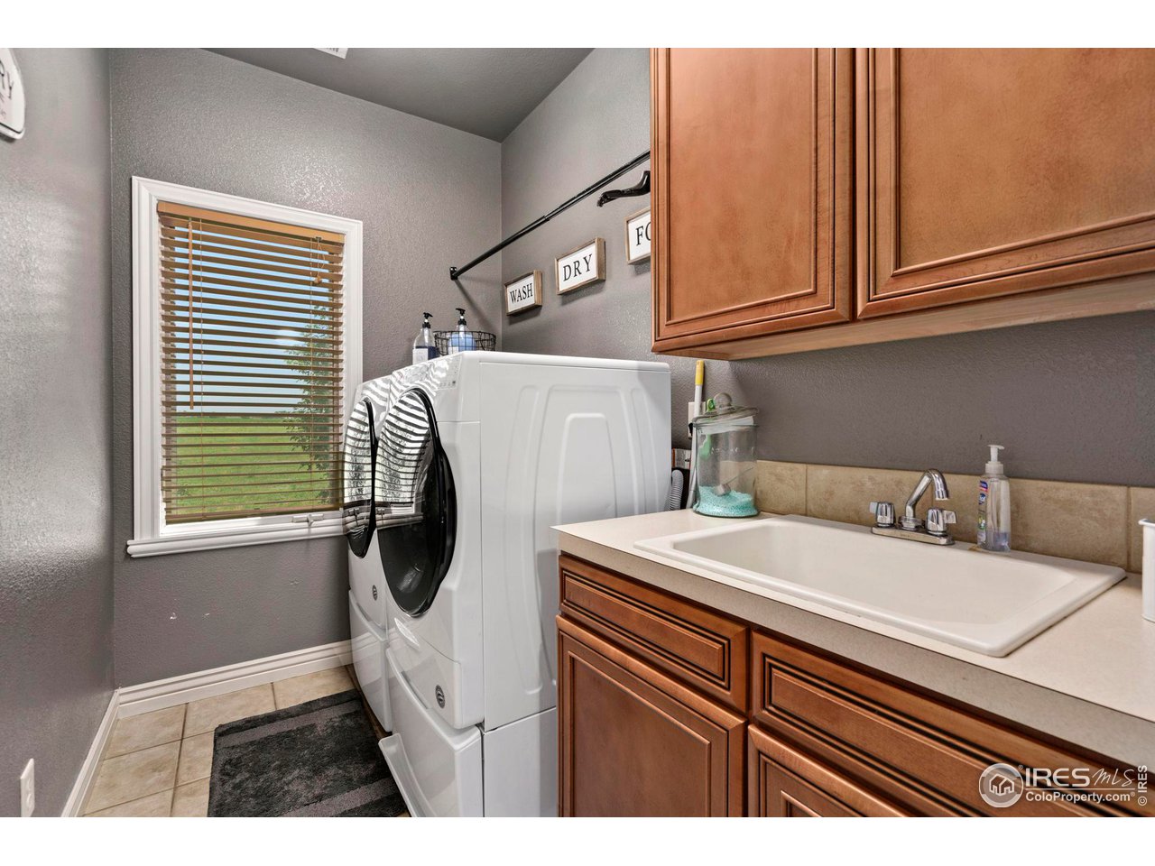 7702 Plateau Road Greeley, CO 80634 - Photo 25 of 40 Upstairs Laundry Room for Convenience with Tile Flooring, Large Window, Sink, Counterspace & Cabinetry