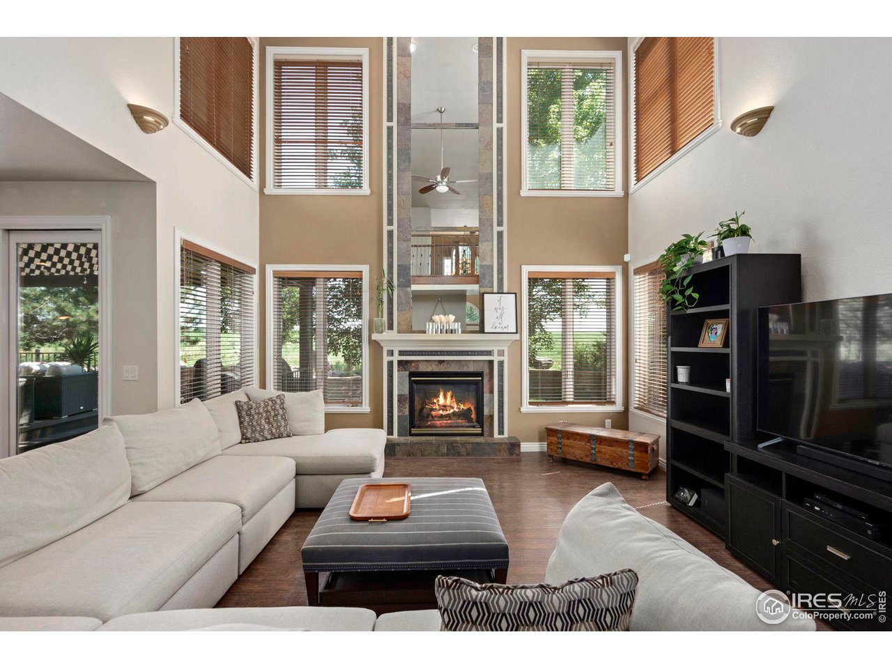 7702 Plateau Road Greeley, CO 80634 - Photo 4 of 40 Great Room with Floor to Ceiling Gas Fireplace & Windows letting in Natural Light & Views of the Mature Trees to the Back