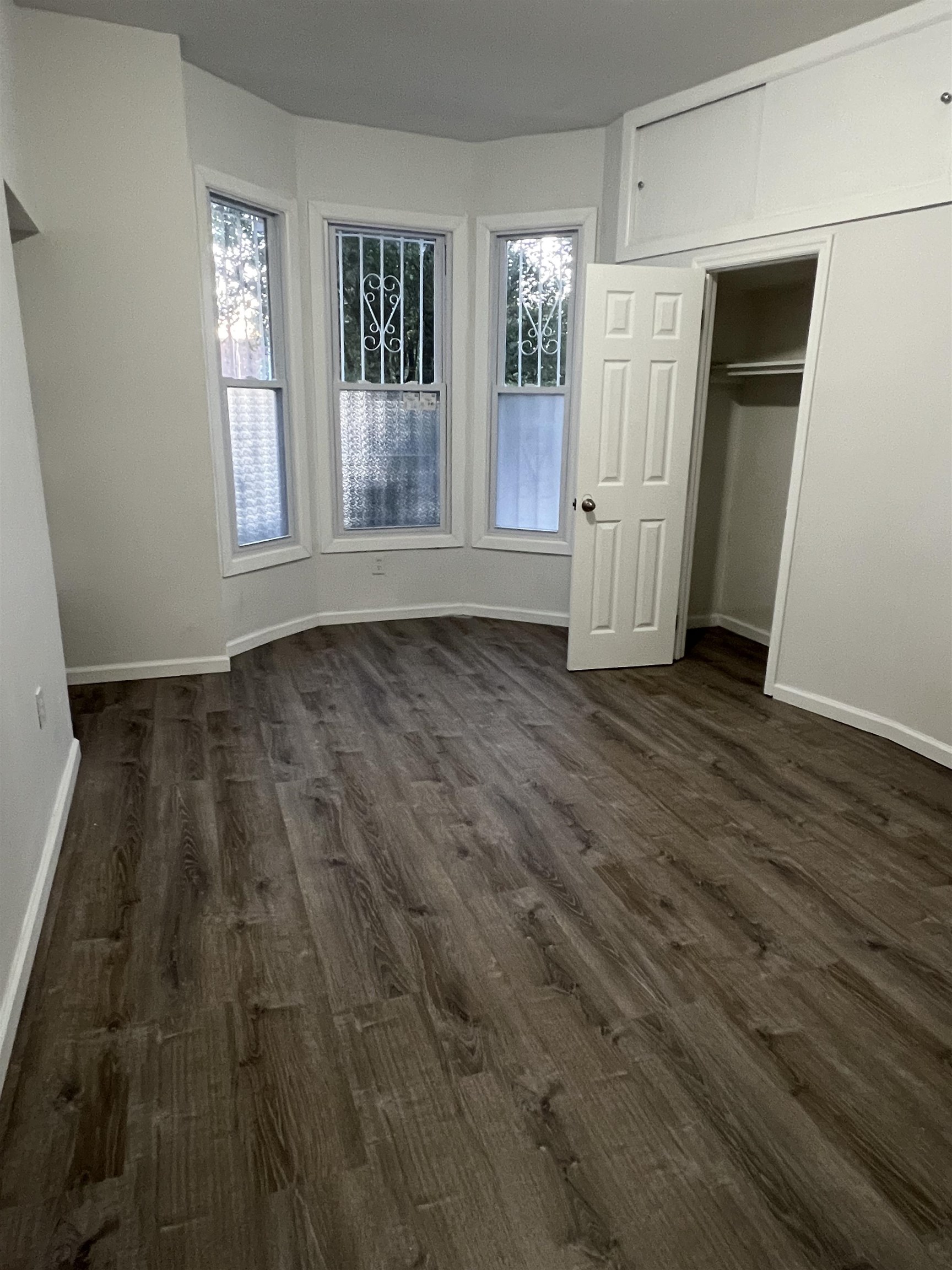 an empty room with wooden floor and windows