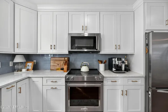 a kitchen with stainless steel appliances granite countertop white cabinets a stove top oven and granite counter