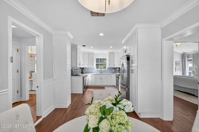 a living room with stainless steel appliances furniture wooden floor and a view of kitchen