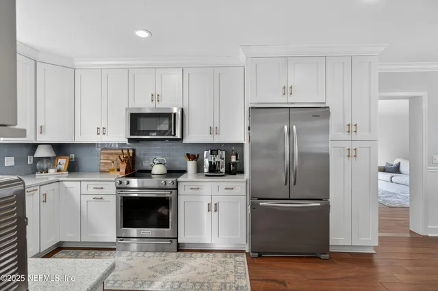 a kitchen with stainless steel appliances granite countertop a refrigerator stove a sink and white cabinets