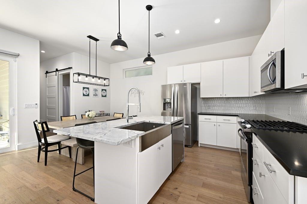 5212 Huisache Street, Unit 2 Austin, TX 78751 - Photo 8 of 30 Kitchen with stainless steel appliances, a barn door, white cabinetry, and a center island with sink