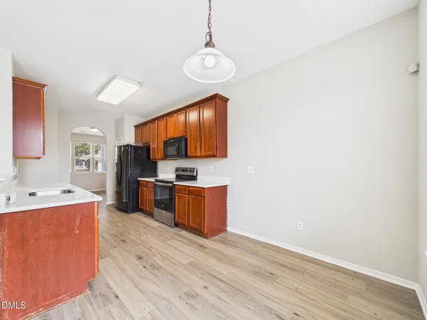 an empty room with wooden floor fireplace and windows