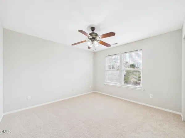 an empty room with a ceiling fan and a window