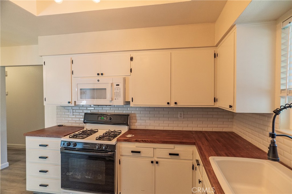 749 Junipero Court Merced, CA 95348 - Photo 14 of 57 a kitchen with granite countertop a sink stove and white cabinets