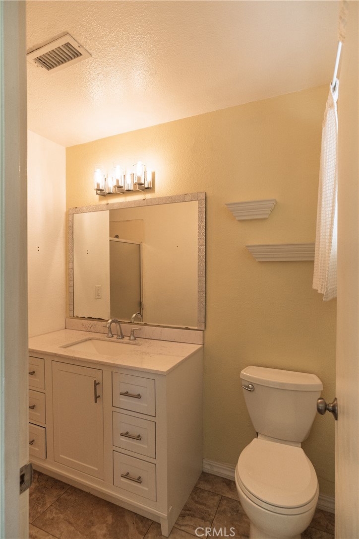 749 Junipero Court Merced, CA 95348 - Photo 25 of 57 a bathroom with a granite countertop toilet sink and mirror