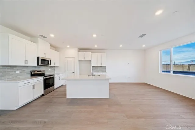 a large kitchen with stainless steel appliances kitchen island a white counter top space and a window