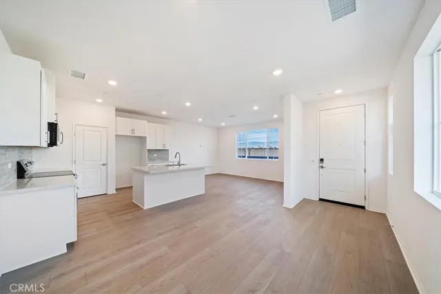 a view of a kitchen with kitchen island a sink wooden floor and a stove top oven