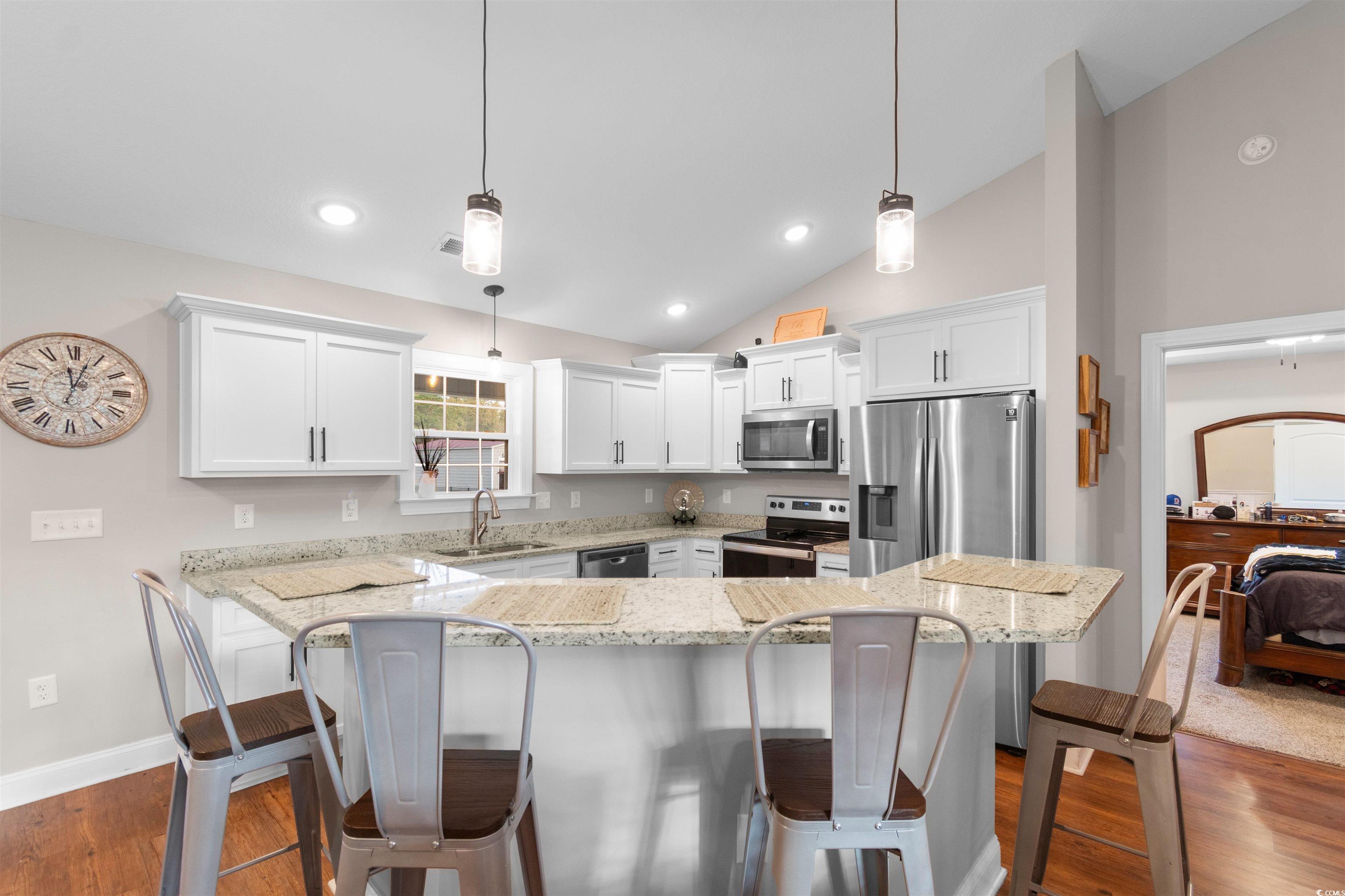 3753 Edwards Road Aynor, SC 29544 - Photo 12 of 38 Kitchen with pendant lighting, a breakfast bar, light stone counters, stainless steel appliances, and vaulted ceiling