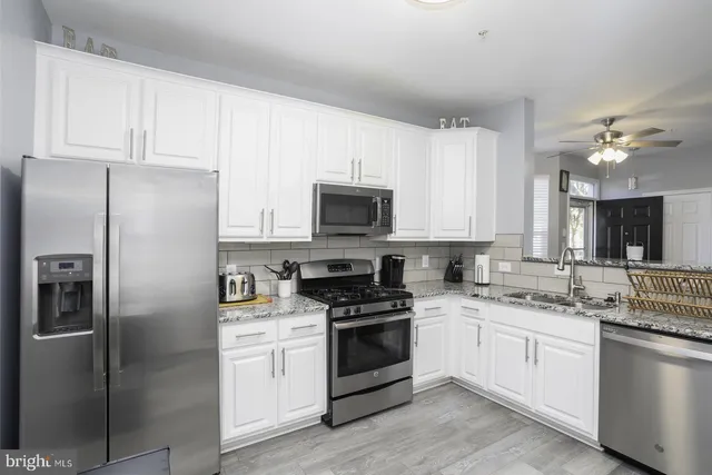 a kitchen with white cabinets white stainless steel appliances and sink