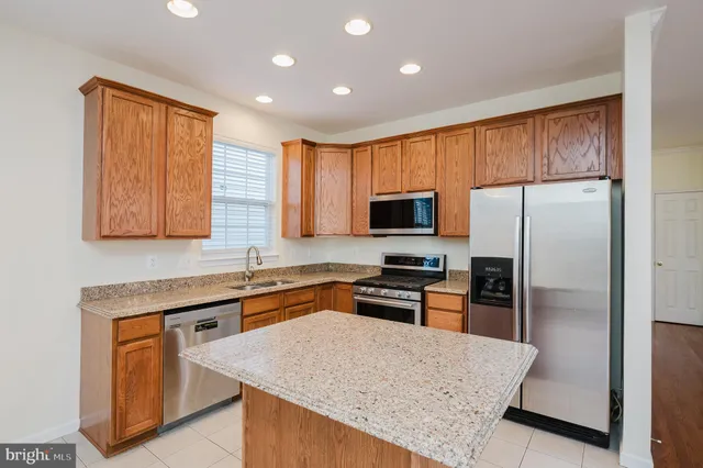 a kitchen with stainless steel appliances granite countertop a refrigerator a stove top oven a sink and dishwasher