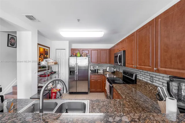 a kitchen with stainless steel appliances granite countertop a refrigerator sink and stove