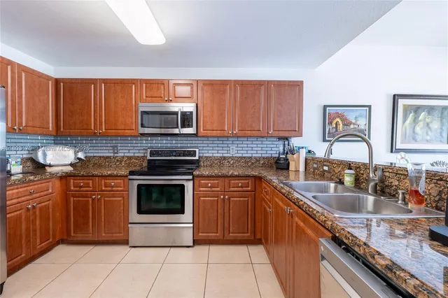 a kitchen with stainless steel appliances granite countertop a stove top oven a sink dishwasher and a microwave oven on the blue kitchen countertops
