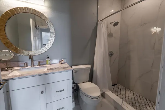 a bathroom with a granite countertop toilet sink and mirror
