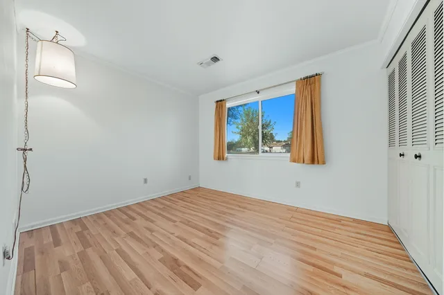 a view of empty room with wooden floor and fan