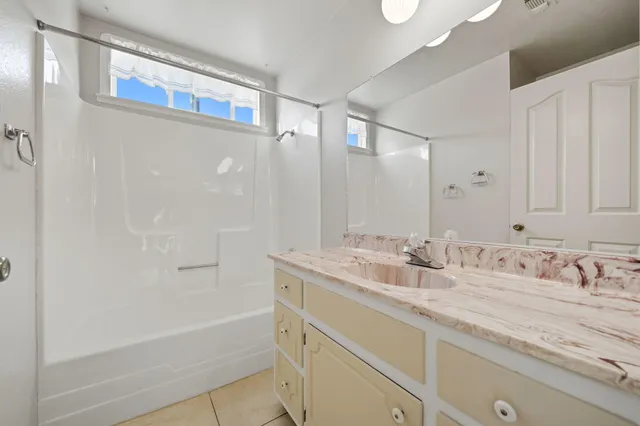 a bathroom with a granite countertop sink mirror and a bathtub