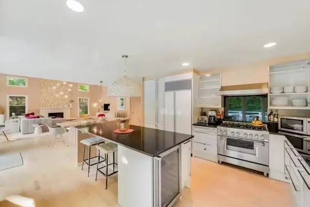 a kitchen with stainless steel appliances a stove a sink a oven a dining table and chairs
