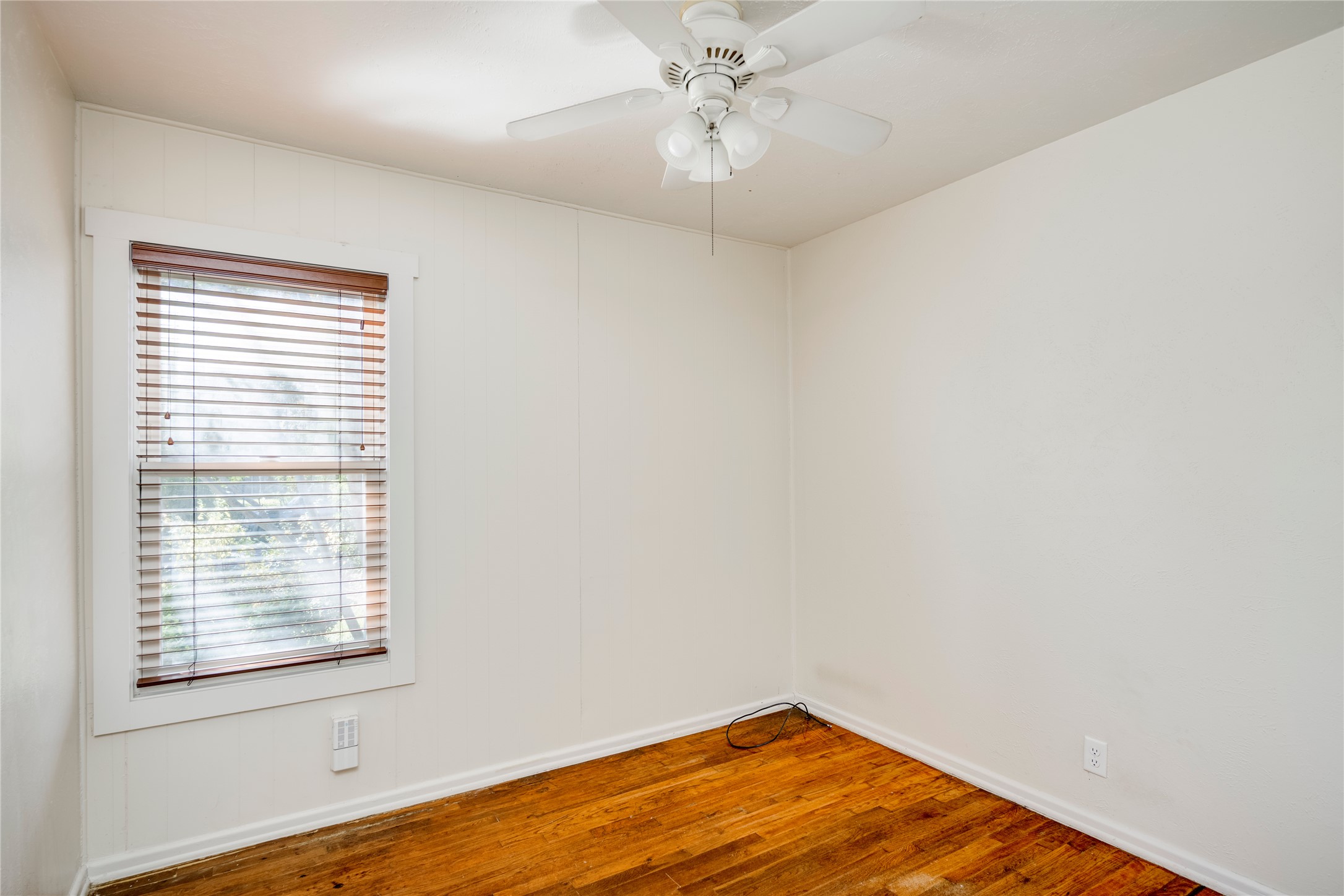 4804 Tanney Street Austin, TX 78721 - Photo 28 of 40 Hardwood floors and a window with blinds define this inviting bedroom space.