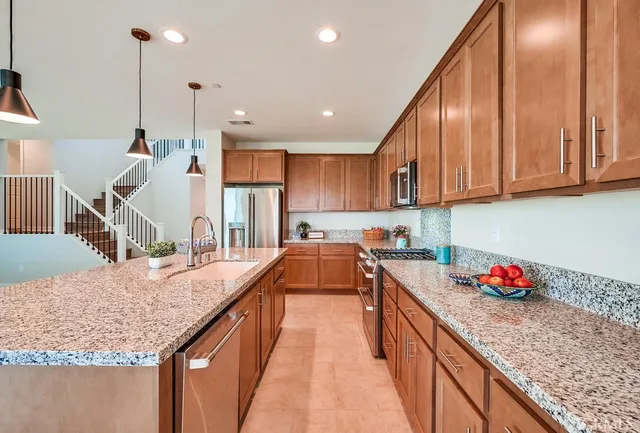 a kitchen with granite countertop kitchen island stainless steel appliances sink cabinets and wooden floor