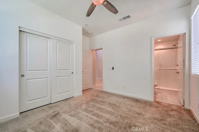 an empty room with closet and a ceiling fan