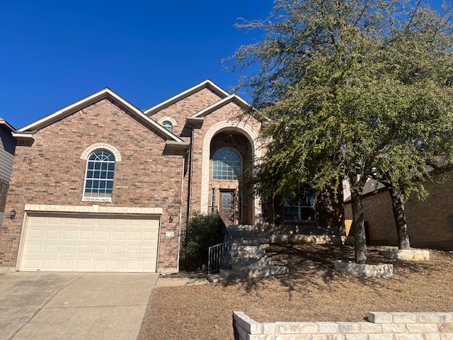 View of front of property with brick siding, driveway, and an attached garage