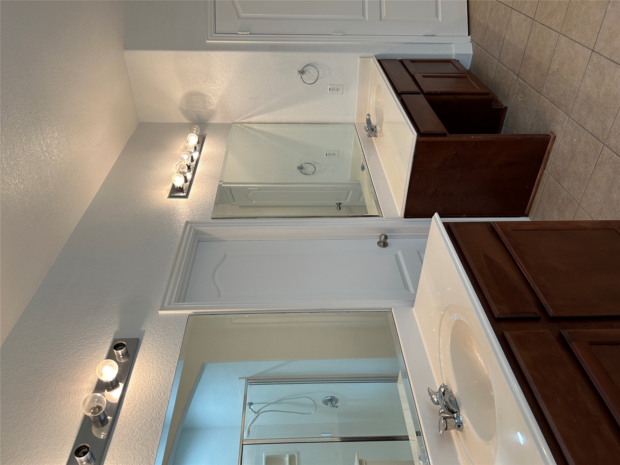 1374 Red Stag Place Round Rock, TX 78665 - Photo 17 of 34 Full bath with a stall shower, two vanities, a textured wall, light tile patterned flooring, and a textured ceiling