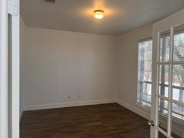 1374 Red Stag Place Round Rock, TX 78665 - Photo 7 of 34 Unfurnished room with dark wood-type flooring, a textured ceiling, and ornamental molding