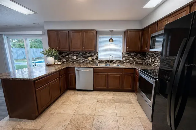 a kitchen with stainless steel appliances granite countertop stove top oven a sink dishwasher a refrigerator and a oven