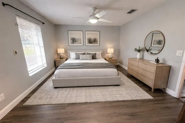 a spacious bedroom with a bed a mirror and windows