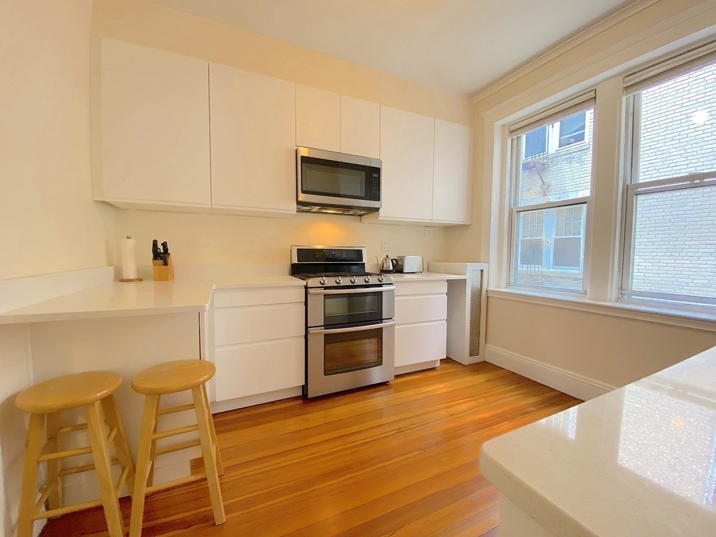 91 Bynner Street, Unit 1 Boston, MA 02130 - Photo 18 of 35 a kitchen with stainless steel appliances kitchen island granite countertop a stove and a white cabinets