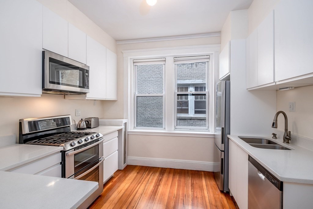 91 Bynner Street, Unit 1 Boston, MA 02130 - Photo 5 of 35 a kitchen with granite countertop a stove a sink and a microwave