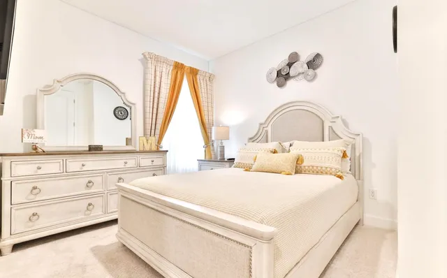 a white bed sitting in a room next to a window