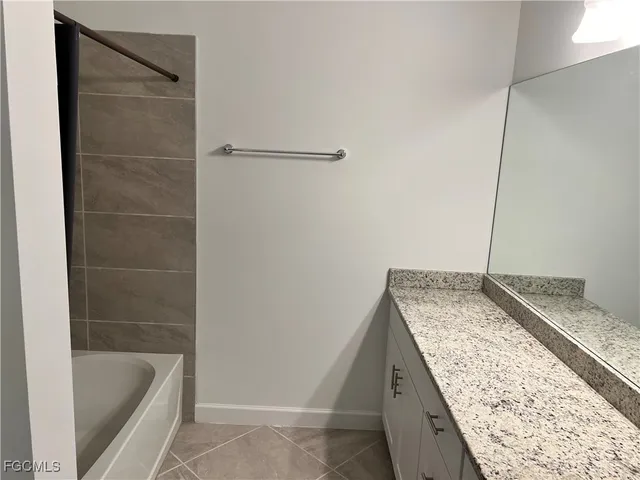 a bathroom with a granite countertop sink and bathtub
