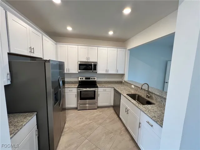 a kitchen with kitchen island granite countertop white cabinets and refrigerator