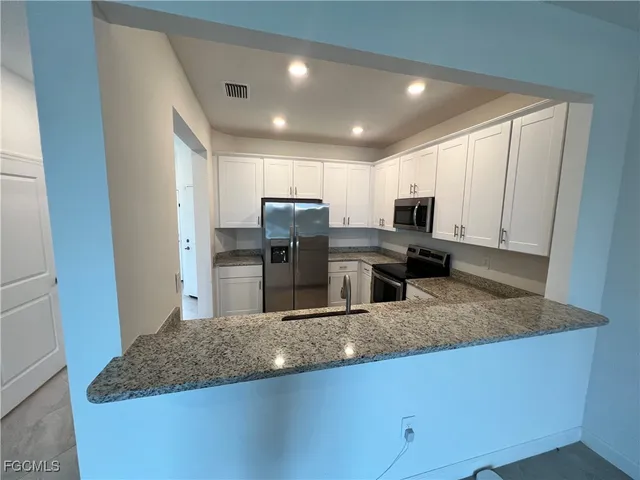 a kitchen with stainless steel appliances granite countertop a sink refrigerator and microwave