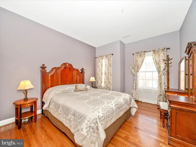 a bedroom with a bed and a dresser with wooden floor