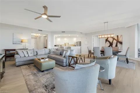 a living room with couches and kitchen view with wooden floor