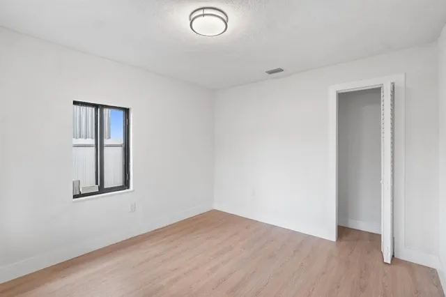 an empty room with wooden floor and window