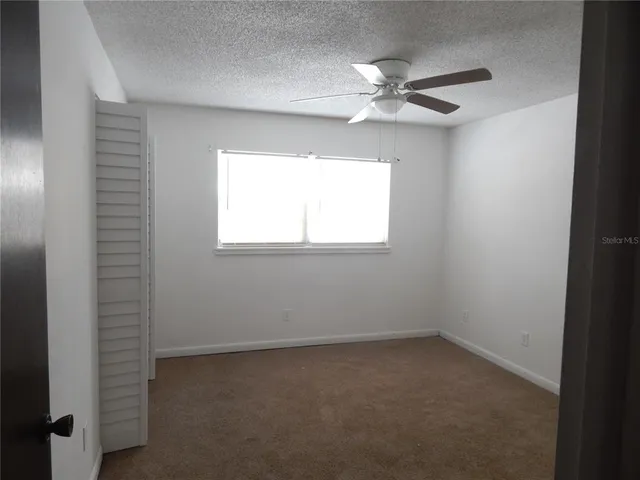 an empty room with a window and a fan